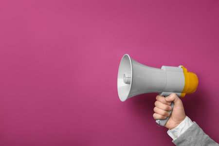 Man holding megaphone on color backgroundの写真素材