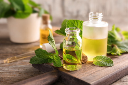 Bottles of essential oil and mint leaves on tableの写真素材