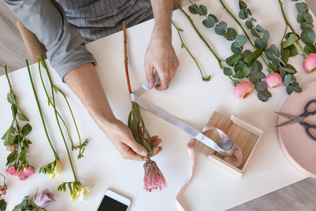 Male florist creating beautiful bouquet at table, top viewの写真素材