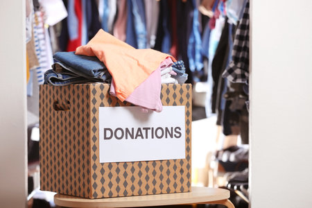 Donation box with clothes on table indoorsの写真素材