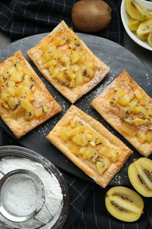 Fresh tasty puff pastry with sugar powder and kiwi served on gray table, flat layの写真素材