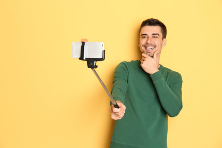 Young handsome man taking selfie against color backgroundの写真素材