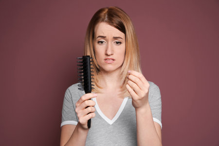 Young woman with hair loss problem on color backgroundの写真素材