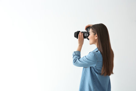 Female photographer with camera on light backgroundの写真素材