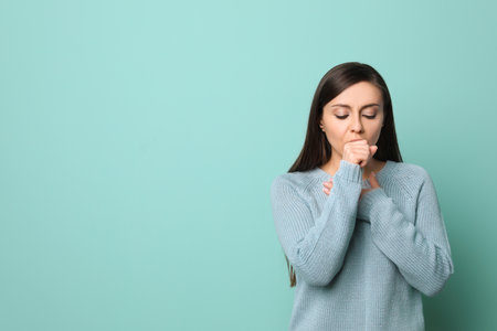Young woman coughing on color backgroundの写真素材