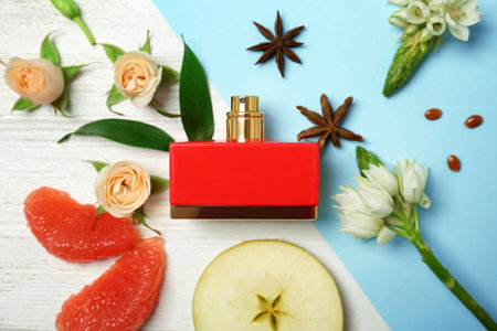 Beautiful composition with bottle of perfume, flowers and fruits on color background, flat layの写真素材
