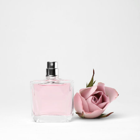 Transparent bottle of perfume with beautiful flower on white background