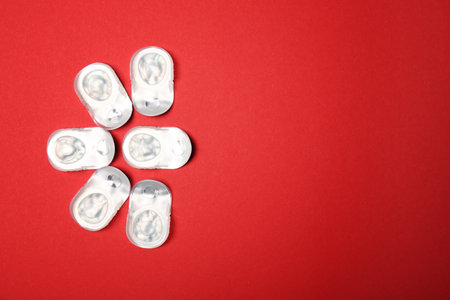 Flat lay composition with contact lenses in packages on color background