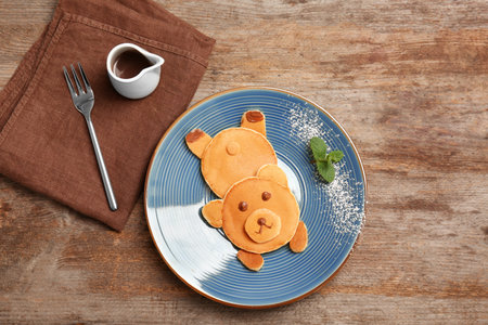 Flat lay composition with pancakes in form of bear on wooden background. creative breakfast ideas for kidsの写真素材