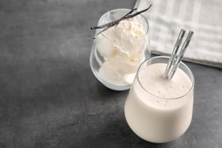 Glasses with milk shake and tasty vanilla ice cream on gray background