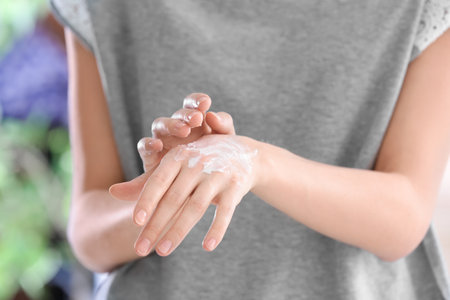 Young woman applying cream on her hands, closeupの写真素材