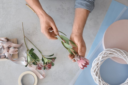 Male florist holding beautiful flower over table, closeupの写真素材