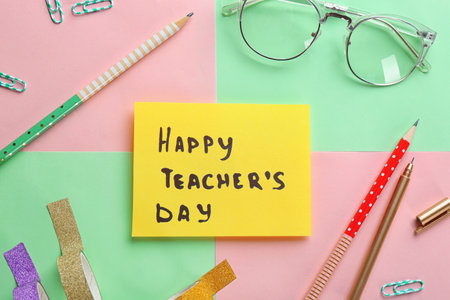 Paper with inscription HAPPY TEACHER'S DAY and stationery on color backgroundの写真素材