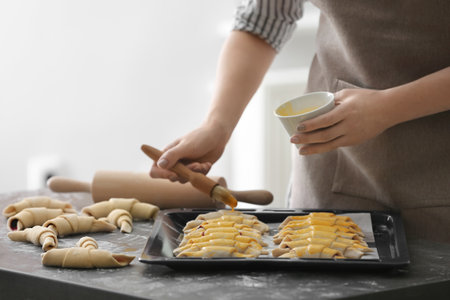 Woman spreading egg yolk on croissants, closeupの写真素材