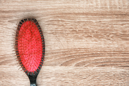 Brush with lost hair on wooden background. Alopecia problemの写真素材