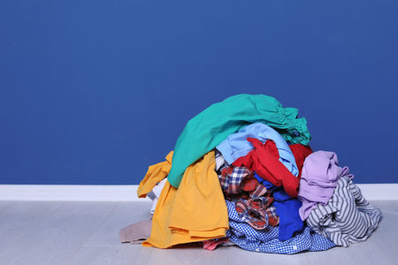 Pile of dirty clothes on floor near color wallの写真素材