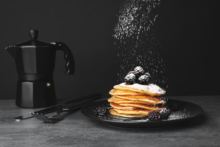Delicious pancakes with berries and powdered sugar served for breakfast on table