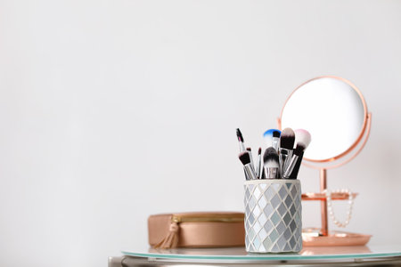 Makeup brushes in holder on table against light backgroundの写真素材