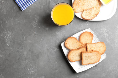Plate with toasted bread and glass of juice on gray background, top viewの写真素材