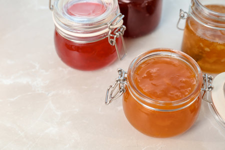 Jars with different sweet jam on table