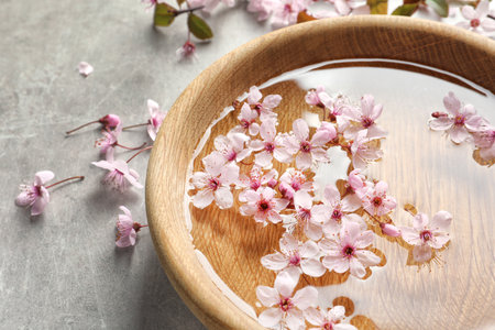 Bowl with water and blossoming flowers on gray backgroundの写真素材