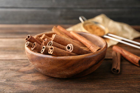 Bowl with aromatic cinnamon sticks on wooden tableの写真素材
