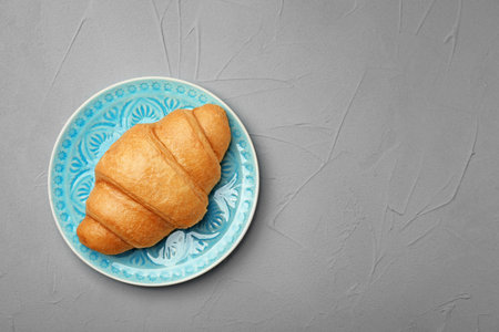 Plate with tasty croissant on gray background, top viewの写真素材