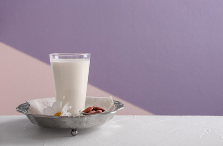 Glass of milk on vintage plate against color backgroundの写真素材
