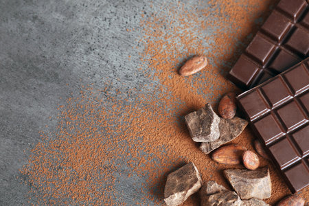 Flat lay composition with cocoa powder and chocolate on gray background