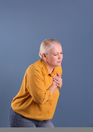 Mature woman having heart attack on color backgroundの写真素材