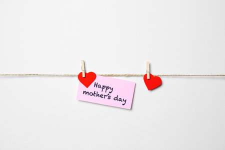 Greeting card with phrase HAPPY MOTHER'S DAY hanging on rope against white background