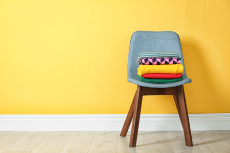 Stack of clothes on chair near color wallの写真素材