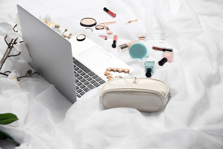 Composition with laptop and makeup products for woman on bedの写真素材