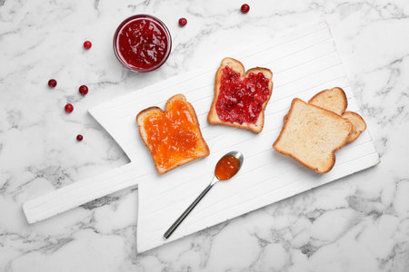 Toasts with various jams on light background, top view