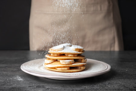 Sprinkling of delicious pancakes with powdered sugar on tableの写真素材