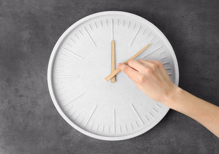 Woman changing time on big wall clock