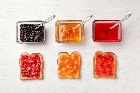 Toasts with various jams on wooden table, flat layの写真素材
