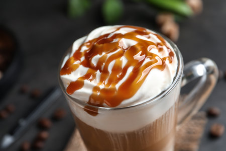 Glass cup with delicious caramel frappe on table, closeupの写真素材