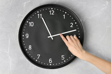 Woman changing time on big wall clock
