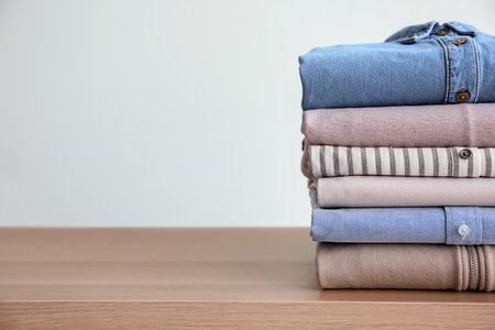 Stack of clothes on table against light backgroundの写真素材