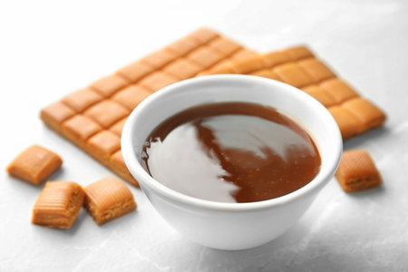 Delicious caramel candies and sauce on light backgroundの写真素材