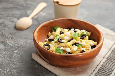 Wooden bowl with delicious pasta salad on gray backgroundの写真素材