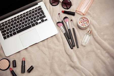 Flat lay composition with laptop and makeup products for woman on fabricの写真素材
