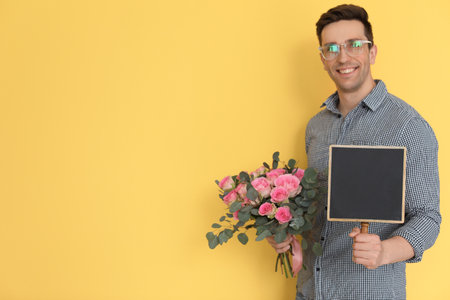 Male florist holding small chalkboard and bouquet on color backgroundの写真素材
