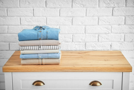 Stack of clothes on table near brick wallの写真素材