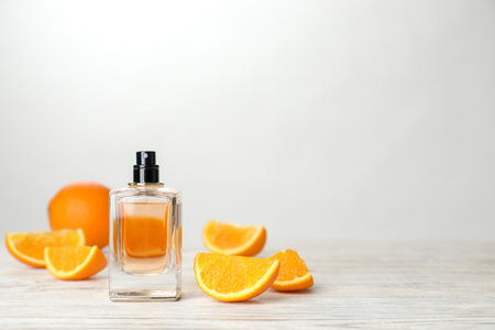 Bottle of perfume and orange on table against light backgroundの写真素材