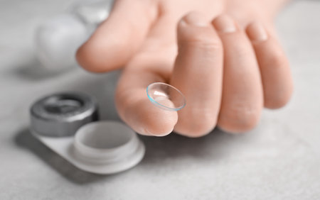 Woman holding contact lens over table, closeupの写真素材