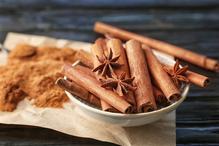 Bowl with aromatic cinnamon sticks and powder on tableの写真素材