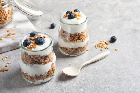 Jars with yogurt, berries and granola on tableの写真素材