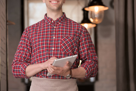 Young waiter with tablet computer at workplaceの写真素材